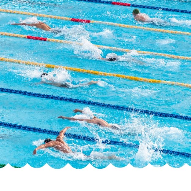 Several swimmers race freestyle in separate lanes, splashing through the pool as Eat Swim Win encourages athlete swimmers and parents to excel with expert swim and nutrition support. Yellow and blue lane dividers separate each lane. Eat Swim Win
