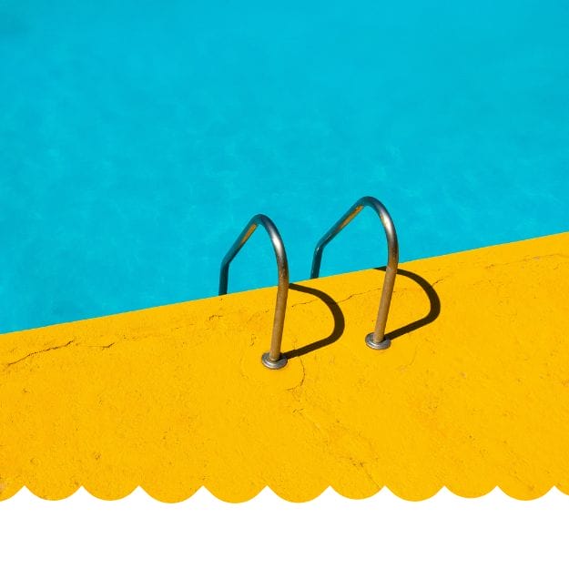 A bright yellow pool deck and curved metal ladder lead into clear blue water under the sun—an inviting spot where athlete swimmers refuel, train, and achieve their nutrition and performance goals. Eat Swim Win